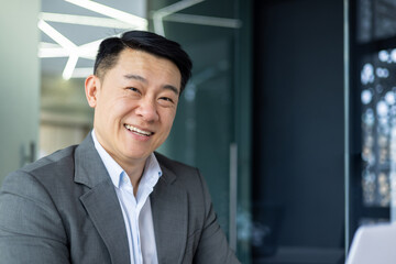 Close up portrait of successful asian financier investor, adult boss smiling and looking at camera,...