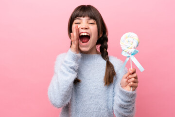 Little caucasian girl holding a lollipop shouting with mouth wide open