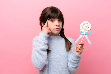 Little caucasian girl holding a lollipop thinking an idea