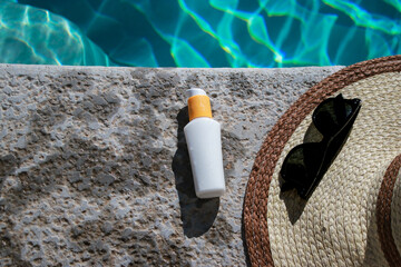 white mock up sunscreen bottle at the pool with sunglasses and summer hat