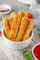 Baked crispy garlic parmesan zucchini sticks served with tomatoes sauce on a gray concrete background. Vegetarian healthy dish. Selective focus.