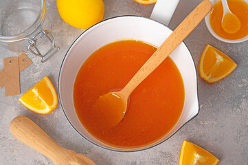 Orange marmalade or orange jam in a pot with fresh fruits on a gray background. Copy space.