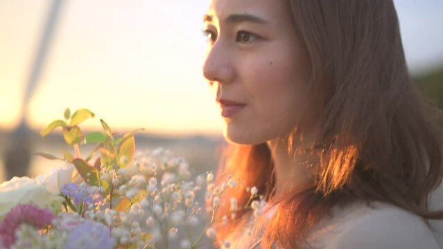 夕方の川辺でブーケを抱えた美しい女性
