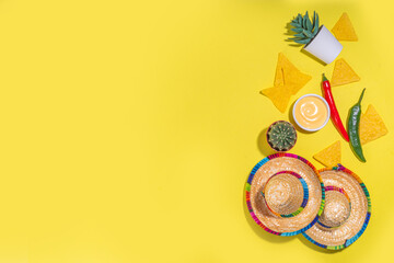 Mexican Cinco de Mayo holiday background with mexican cactus, nachos chips, guitars, sombrero hat and chilli pepper, Bright yellow flat lay with traditional Cinco de Mayo decor and party accessories