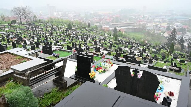 Orthodox cemetery during heavy rain. Graves in graveyard. Marble monuments in the cemetery.