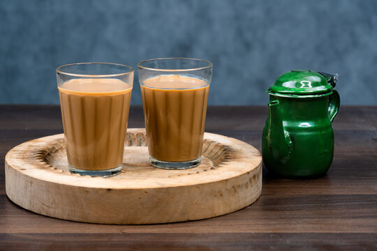 Karak Milk Chai glasses with chanak (tea pot) famous indian tea on textured background 