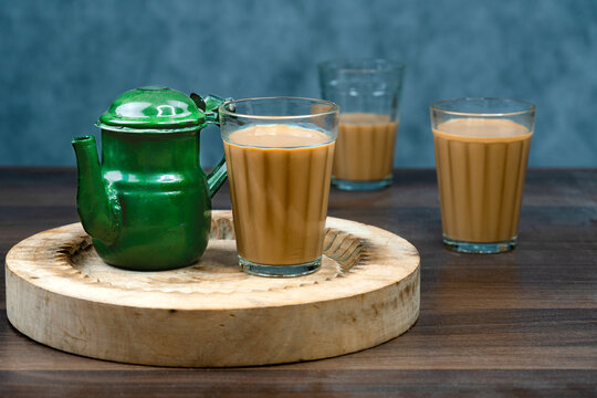 Karak Milk Chai glasses with chanak (tea pot) famous indian tea on textured background 