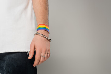 Cropped view of homosexual man with lgbt bracelet on hand standing isolated on grey.