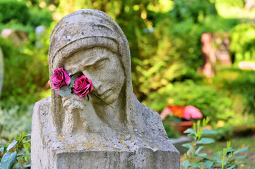 Die Trauernde mit betenden Händen und Blumen vor Gräbern