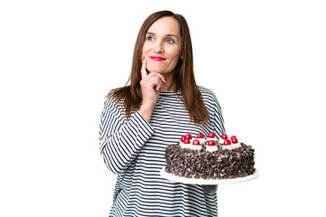 Middle age caucasian woman holding birthday cake over isolated chroma key background thinking an idea while looking up