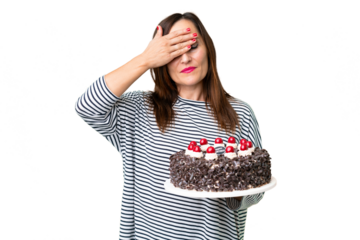 Middle age caucasian woman holding birthday cake over isolated chroma key background covering eyes by hands. Do not want to see something