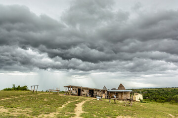 Fototapeta na wymiar Regenwolken über einfachen Holzhütten, Queen Elizabeth Nationalpark, Uganda, Afrika