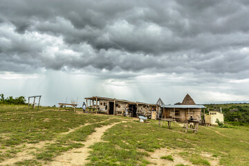 Fototapeta premium Regenwolken über einfachen Holzhütten, Queen Elizabeth Nationalpark, Uganda, Afrika