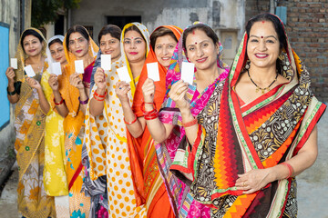 Group of happy traditional indian women wearing sari standing in queue showing blank id card....
