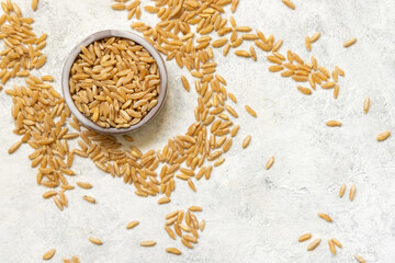 Bowl of raw dry rye grain on white table top view, copy space