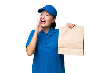 Young Asian woman taking a bag of takeaway food over isolated background shouting with mouth wide open to the side