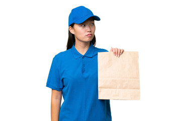 Young Asian woman taking a bag of takeaway food over isolated background looking to the side