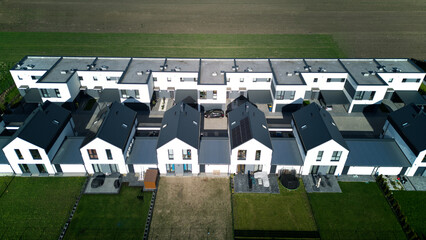 Aerial spring view of warm sunny neighbourhood community houses with single street and field...