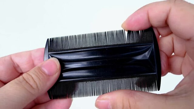 black plastic comb, fine comb, tool in female hands, used to comb out crusts on head of babies, fighting seborrheic dermatitis, combing head lice and nits from hairline