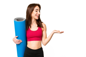 Young sport caucasian woman going to yoga classes while holding a mat over isolated chroma key background with surprise expression while looking side