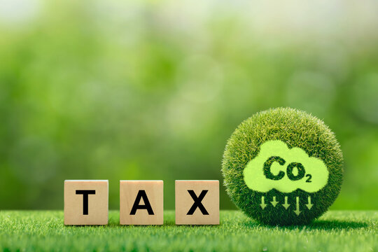  Carbon tax, CO2 tax, words TAX on a wooden cube with co2 icon on a green ball. environmental and social responsibility business concept. Taxation for nature pollution. Controlling carbon emission