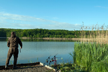 Obraz premium a fisherman throws a fishing rod into a large lake