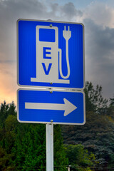 EV charging station road sign on dramatic sky background