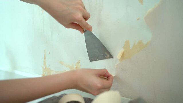 Asian woman fixing and removing a broken wallpaper by herself. 