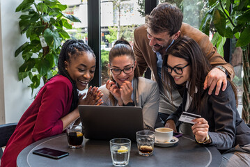 Young senior web developers small company owners new to the job market, developing a new internet application for a banking credit card payment system, sitting in a cafeteria working on a coffee break