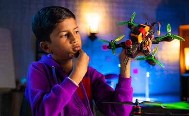 Young indian teenager kid thinking about drone flight at home during night - concept of brainstorm,...