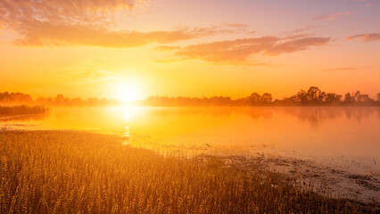 Fototapeta na wymiar Scenic view of beautiful sunrise or dawn above the pond or lake at spring or early summer morning.