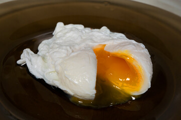 Poached egg on a black plate, close-up.