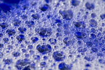 Closeup of blue translucent soap bubbles floating on the water surface, perfect for backgrounds