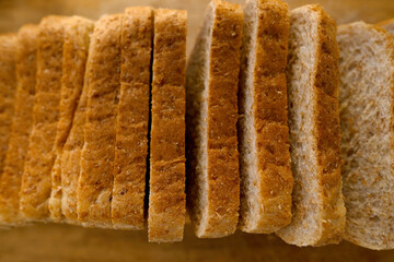 close-up toast appetizing fresh wholemeal bread with bran sliced in layers on wooden board, wheat, multigrain bread topview, bakery pastries, gluten products, diet, wholesome food, healthy eating