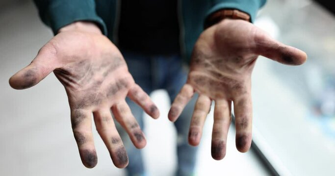 A man shows dirty hands, a close-up. Hands in soot, car breakdown, palms in the swamp, shallow focus