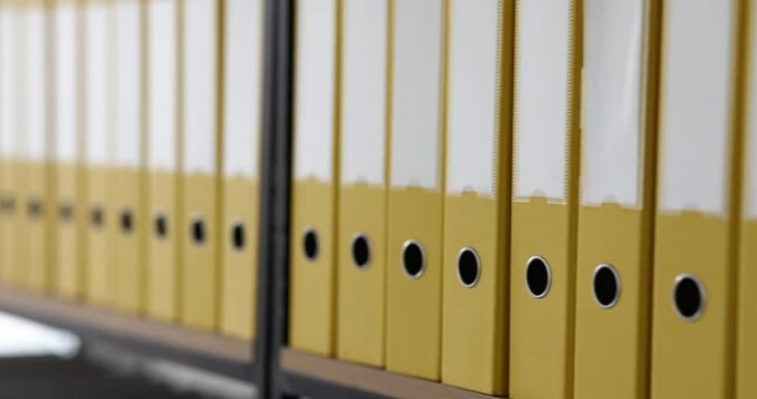 Yellow folders in a row on the rack, close-up. Optimization of storage of documents in the office