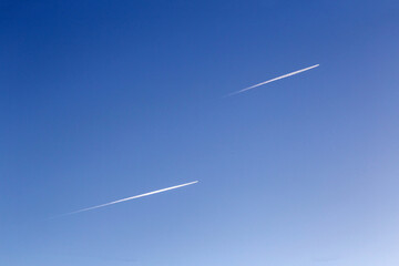 Dos aviones volando en paralelo en un cielo azul, dejando estelas blancas a su paso.