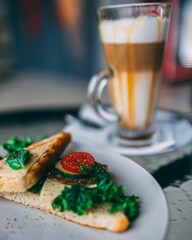 Vertical shot of a toasted sandwich and a glass of latte on a cafe table