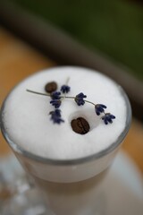 a white cup topped with liquid and coffee beans and flowers