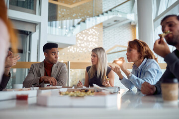 Young business people are chatting and enjoy eating a pizza during a lunch break in the company building. Business, people, company - 595004765