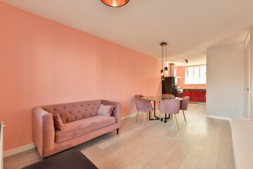 a living room with pink walls and white flooring in the center of the room is a couch, two chairs and a table