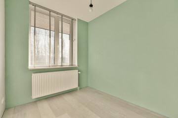 an empty room with light green walls and wood flooring on the right side of the room, there is a rad window