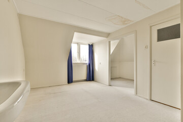 an empty room with white walls and blue drapes on the door is open to let in light from the window