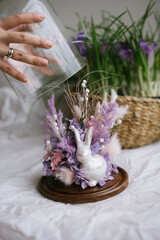 Beautiful easter composition of dry purple and white flowers and a ceramic bunny rabbit decorative figure, close up vertical view 