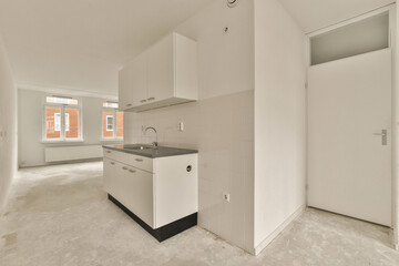 an unfinished kitchen with white cabinets and black counter tops, in a room that is being renovated to make way for new appliances