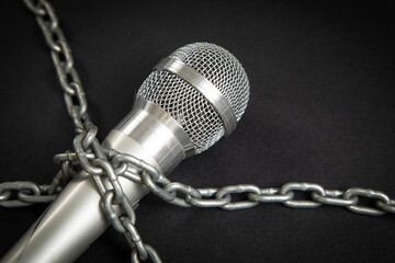Microphone tied with chains on the black background.