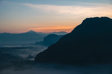 Fototapeta na wymiar Picturesque sunrise above a mountainous landscape with a valley below shrouded in a misty fog