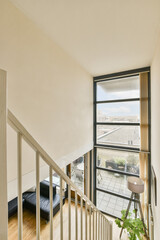 a living room with wood flooring and white walls, looking out onto the street from an upstairs...