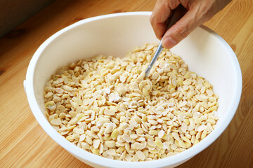 Hand Using Spoon to Mix Powdered Tempeh Starter with Boiled Soybeans