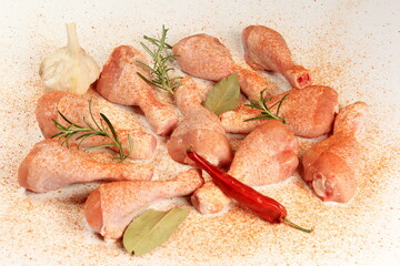 Raw chicken legs with spices and pepper  on a white background. Fresh chicken drumsticks background